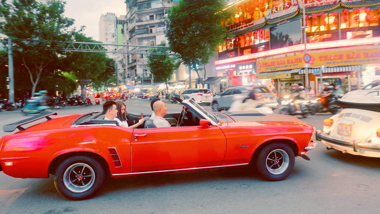 Ford Mustang mui trần đỏ len giữa Đường phố Chợ Lớn lên đèn